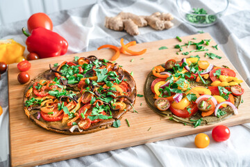 .raw vegetarian pizza with onions, peppers, tomatoes, fresh herbs on a cutting board. Lies on the...
