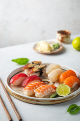 Set of sushi and maki on plate with soy sauce and chopsticks on white background. Top view with copy space