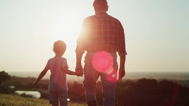 Rear view video of grandfather and grandson walking at sunset. Shot with RED helium camera in 8K.