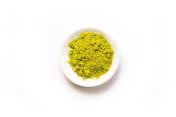 Green powder of Japanese matcha tea on a platter, isolated on a white background. Loose powder. Space for text. Cafe and cooking, an ingredient for an invigorating drink