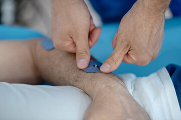 Close-up of physiotherapist hands applying pad on patient wrist