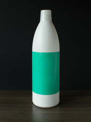 White plastic bottle with green label on dark background. Bottle mock-up.