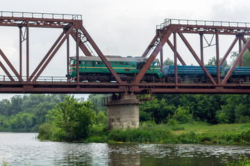Freight train rides on a railway bridge over the river