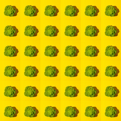Fototapeta premium Seamless pattern of top view ripe juicy green head of broccoli cabbage on bright yellow background.