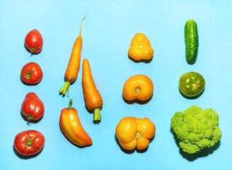 Top view food knolling of vegetables on blue backdrop. Food knolling. Trendy hard shadows.