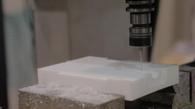 Automatic cnc turning milling machine cutting white acrylic artificial stone workpiece at factory, plant, exhibition: close up. Metalworking, engraving, industrial, technology, manufacturing concept