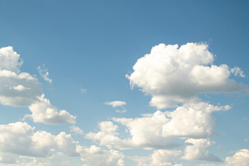 Naklejka na ściany i meble White large cumulus clouds against the blue sky.