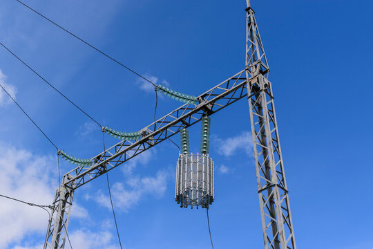 A line trap (high-frequency stopper) is a maintenance-free parallel resonant circuit. Metal constructions, high-voltage wires, glass insulators.    Background - the sky with clouds.