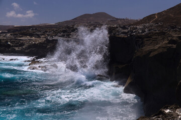 North coast of Gran Canaria, Canary Islands, Banaderos area, waves are breaking against elevated rock with salt evaporation ponds Salinas de Bufadero
