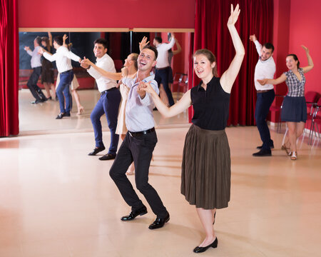 Cheerful group people dancing lindy hop in pairs in dance hall
