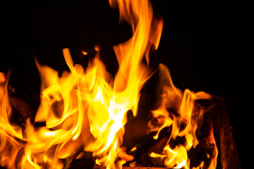 Fire on a dark background. Fire from firewood close up. Flaming burning sparks close-up, fire patterns. Red and orange Infernal glow of fire in the dark.