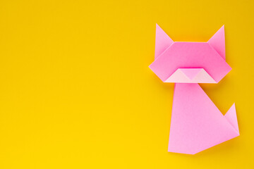 pink origami cat on yellow background