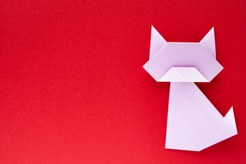 light purple origami cat on red background