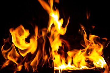 Fire on a dark background. Fire from firewood close up. Flaming burning sparks close-up, fire patterns. Red and orange Infernal glow of fire in the dark.