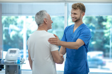 Obraz premium Young doctor shaking hand to elderly patient