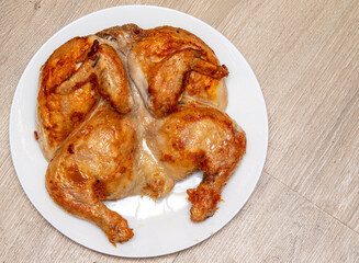 Roasted tobacco chicken on a white plate on a wooden table.