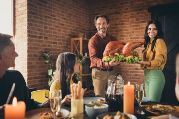 Portrait of nice attractive cheerful big full family meeting wife husband married couple carrying plate fresh homemade turkey serving table occasion at modern loft industrial brick interior house