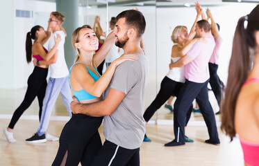 Dancing positive russian couples learning salsa at dance class