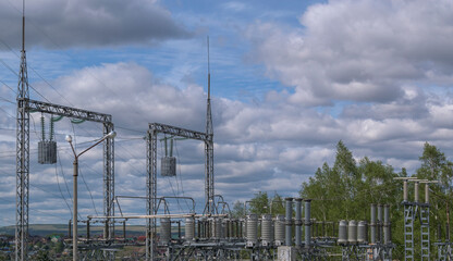 Electrical substation. Electrical equipment, structures, wires, line trap. Background - blue sky with clouds, green trees, houses. Concept - accumulation, collector, transmission of electricity.