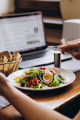 table with dinner dishes and laptop on background. An ordinary dinner busy with many chores of a businessman without distraction from work
