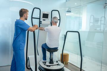 Man on special simulator and observing rehabilitation therapist