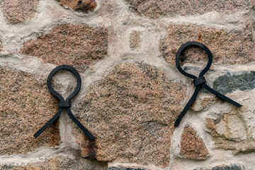Old rock wall with forged iron loops as reinforcement