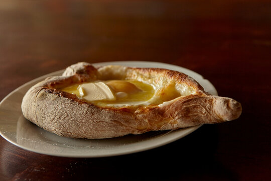 Caucasian cuisine khachapuri with egg and cheese. A melted piece of butter. Khachapuri in the shape of a heart