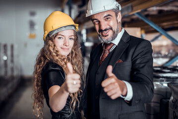 Engineer woman and businessman wearing a hardhat standing at cargo merchandise or goods warehouse and check for control loading from Cargo freight ship for import and export. Teamwork concept