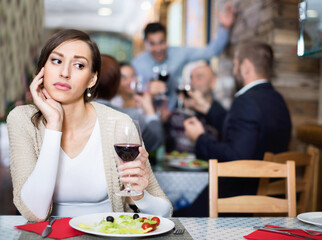 Portrait of upset dreary melancholy woman in the restaurant with salad and wine
