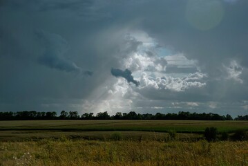 Fototapeta premium storm clouds over the field, sun rays, sunlight and sunshine 