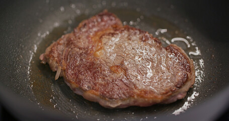 Fried steak on the pan in kitchen