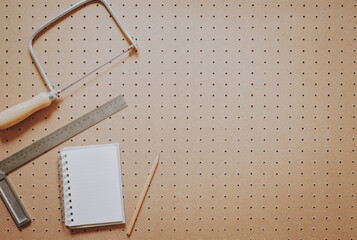Top view of woodworking tools and notebook on a pegboard with blank copy space