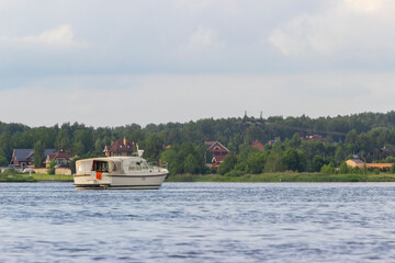 A beautiful white yacht stands on the lake near the cottage village in sunbeams. Life of people away from the city in a Villa. luxury holiday abroad concept