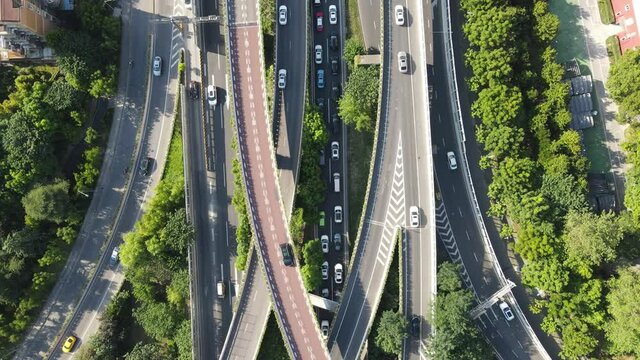 Drone aerial view of curved overpass multi lane highways junction in sunshine day. Travel tourism industry transportation concept footage. Trees and green plant around the highway in Shanghai China.