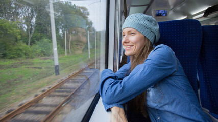 beautiful girl traveling by train and using phone loking out of window