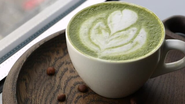 white coffee cup with green matcha latte art rotating on a stone plate side view. template for summer drink menu of cafe and restaurant
