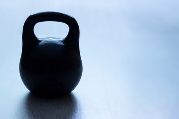 Obraz na płótnie Canvas Old sports weightlifting equipment - cast iron kettlebell on a blue background with copy space.