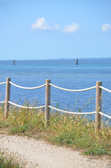 
path bordered by wooden poles with ropes overlooking the lagoon