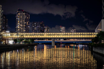 View of the fotbridge connecting the building across the canal in Yokohama during night time.