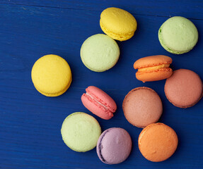 stack of multi-colored round baked macarons cakes on a blue wooden background