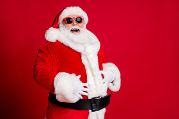 Photo of retired old man grey beard hands big belly laughing out loud kid tell great christmas joke wear santa costume gloves coat sunglass headwear isolated red color background