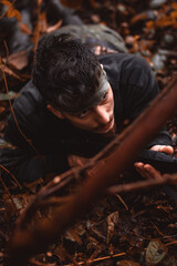 Soldier or revolutionary member or hunter aiming with gun in his hand in camouflage in the forest floor, hunt concept