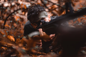 Soldier or revolutionary member or hunter aiming with gun in his hand in camouflage in the forest floor, hunt concept