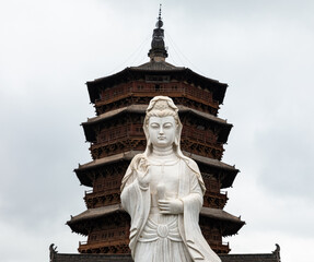 Guanying statue at Fogong Temple in Yingxian, Shuozhou, Shanxi, China. Wooden Pagoda or Sakyamuni Pagoda on background, world's tallest & oldest existing wooden tower. 