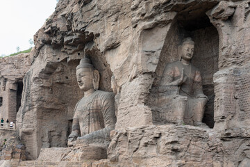 Seated Buddha statue in Cave 20 & caves in weast part at Yungang Grottoes, Datong, Shanxi, China. Created in 5th century during Northern Wei period. UNESCO World Heritage.