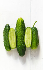 A view from above of the fresh raw cucumbers that lie on a light wooden background