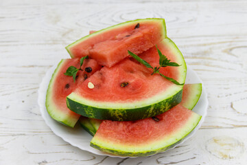 Fresh ripe sliced watermelon in white plate on a white wooden table