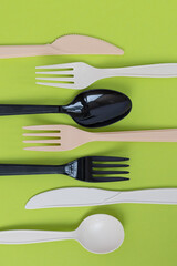 Top view of plastic tableware against vivid green background, flat lay