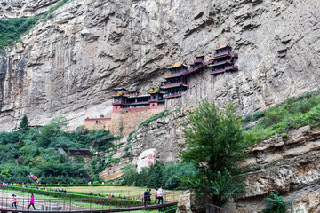 Tourists cross bridges to Xuankong or Hanging Temple on cliff at Mount Heng in Hunyuan, Datong, Shanxi, China. Over 1500 years old, mixing Buddhism, Taoism & Confucianism. Attraction & heritage.