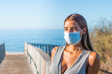 Unhappy girl, young upset desperate woman in medical protective mask on her face against...